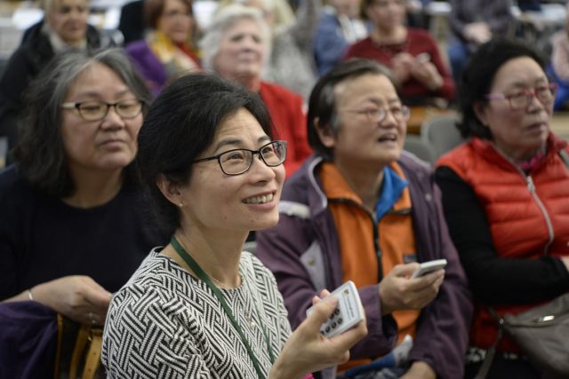 A group of women holding voting handsets.