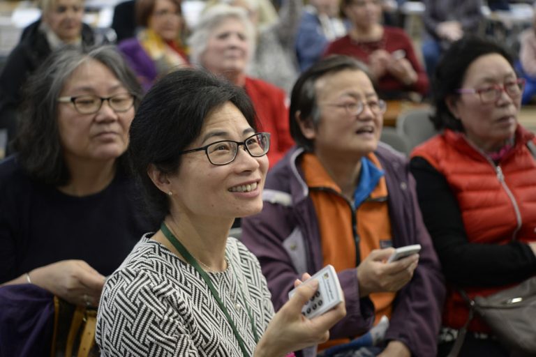 A group of women holding voting handsets.