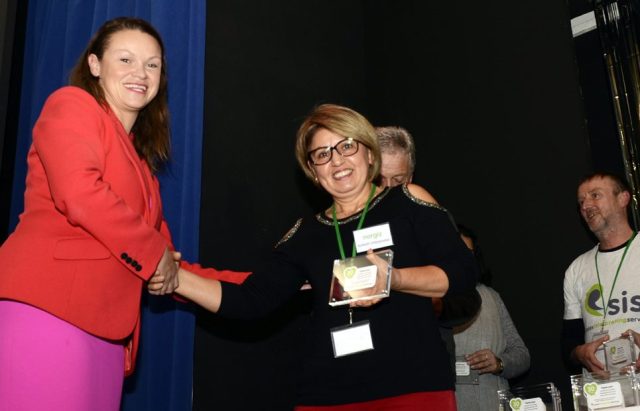 A female interpreter being presented with an award by Bella Sankey.