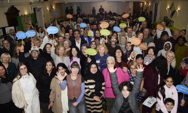 A large group of people smiling and waving and holding speech bubbles in many languages.